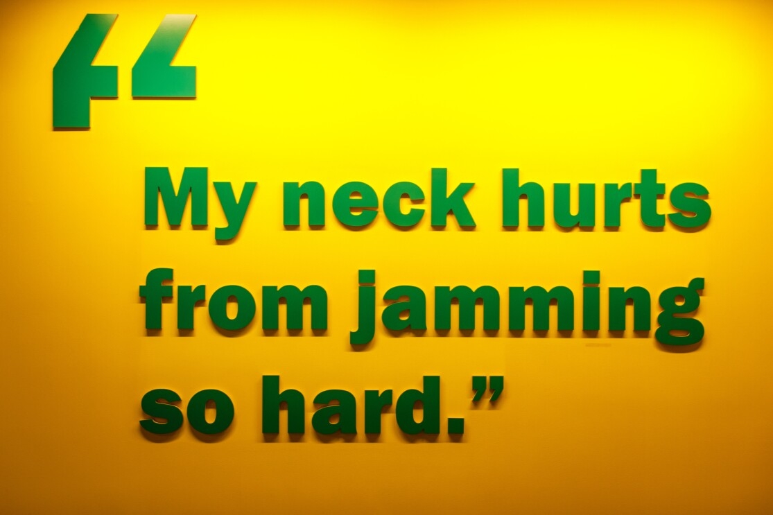 A quote in green lettering on an orange wall at the Amazon Music office in Seattle, WA. It reads "my neck hurts from jamming so hard."