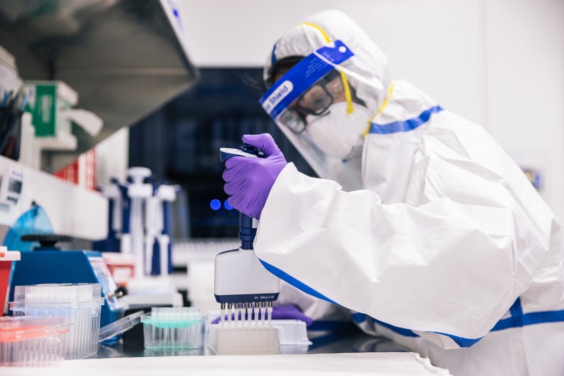 Two people in PPE look at lab samples.